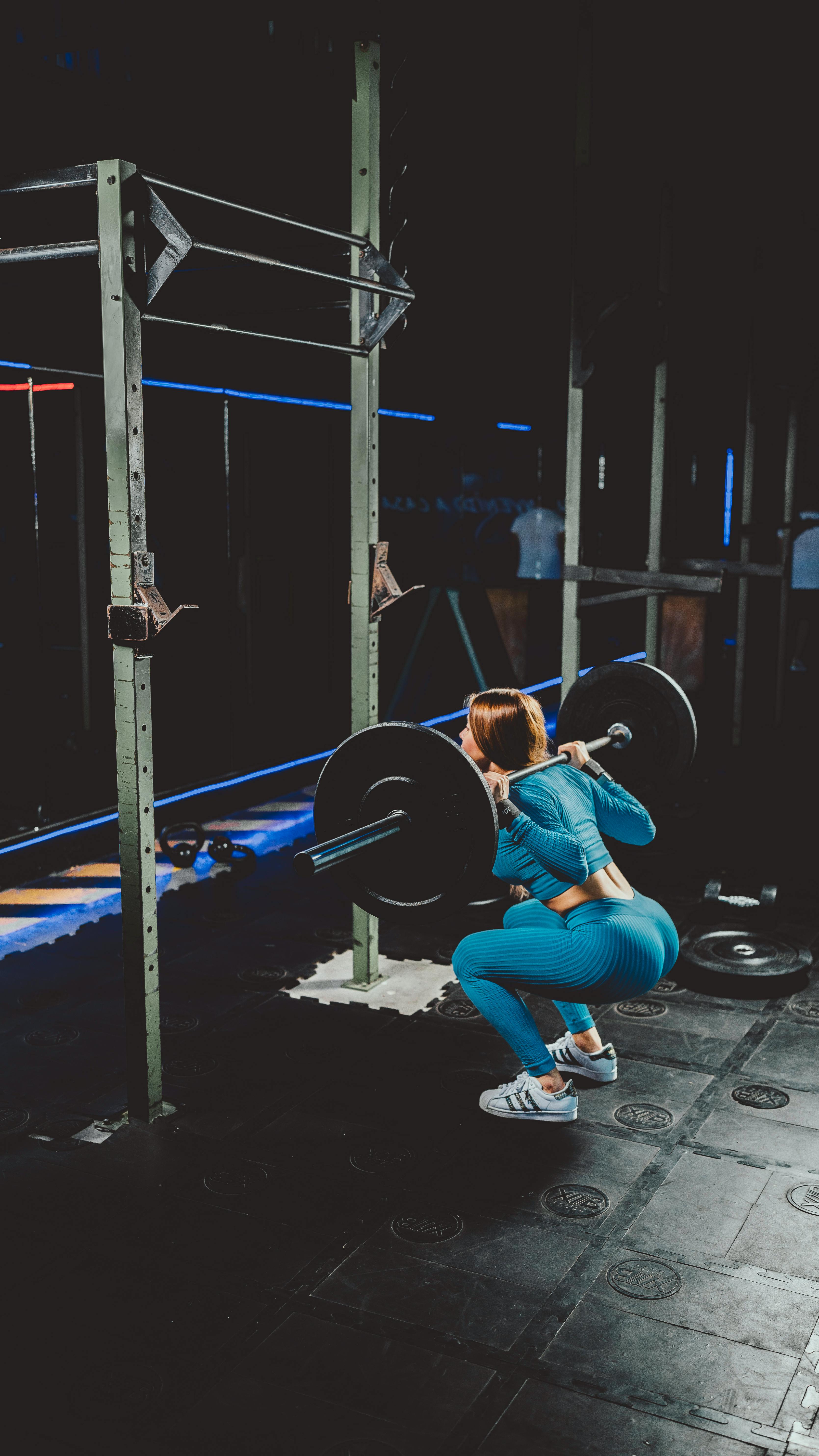 Frau beim Kniebeugen mit Langhantel – Muskelaufbau